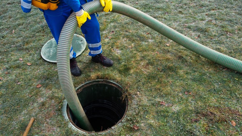 Image of a septic expert, pumping a septic tank.
